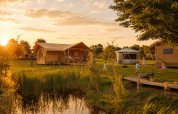 Glamping tent at Holiday park Eigen Wijze in the Netherlands at sunset, with children playing nearby.