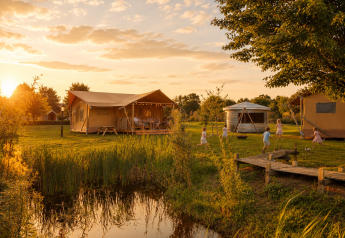Tienda glamping en Holiday park Eigen Wijze, Países Bajos, al atardecer con niños jugando cerca.