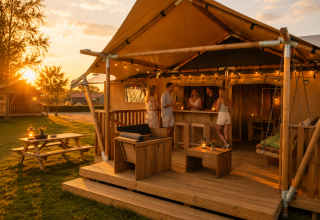 Safari-Glampingzelt im Ferienpark Eigen Wijze in den Niederlanden mit Menschen bei Sonnenuntergang.