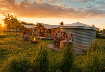 People enjoy a summer evening at a glamping tent site with campfire at Holiday park Eigen Wijze in NL.
