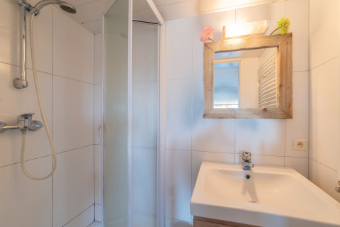 Bagno luminoso a Le Chalet sous les Hetres in Belgio con doccia, lavandino e specchio con cornice in legno.