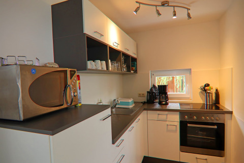Moderne kitchenette in het verblijf 'On the Beach' in Duitsland met microgolf, oven en koffiemachine.