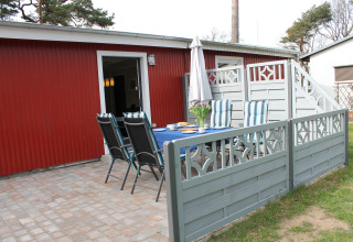 Outdoor patio at the lodge 'On the Beach' in Germany, featuring table, chairs, and a red building backdrop.