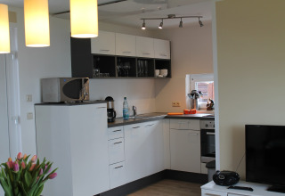 Modern kitchen and living area at the lodge ‘On the Beach’ in Germany, fully equipped with appliances.