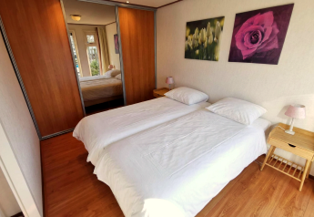 Hyggeligt soveværelse i Chalet Basic på De Woudhoeve, Nederlandene, med to enkeltsenge og spejlskab.