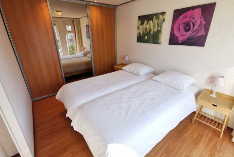 Sfeervolle slaapkamer in Chalet Basic op De Woudhoeve, Nederland, met twee eenpersoonsbedden en spiegelkast.