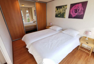 Sfeervolle slaapkamer in Chalet Basic op De Woudhoeve, Nederland, met twee eenpersoonsbedden en spiegelkast.