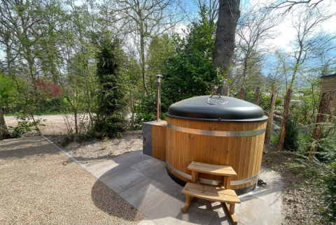 Holzbadetonne mit Abdeckung bei Hackfort Wood 6 Lodge im De Utrechtse Heuvelrug, Niederlande, im Grünen.