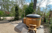 Holzbadetonne mit Abdeckung bei Hackfort Wood 6 Lodge im De Utrechtse Heuvelrug, Niederlande, im Grünen.