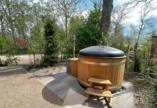 Holzbadetonne mit Abdeckung bei Hackfort Wood 6 Lodge im De Utrechtse Heuvelrug, Niederlande, im Grünen.