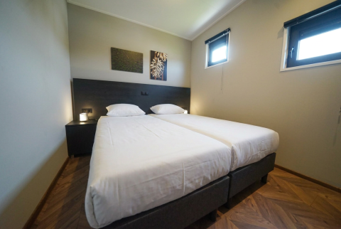 Een kamer in lodge Just Nature op De Utrechtse Heuvelrug, Nederland, met twee eenpersoonsbedden en minimalistisch interieur.