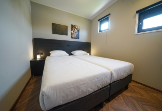 Een kamer in lodge Just Nature op De Utrechtse Heuvelrug, Nederland, met twee eenpersoonsbedden en minimalistisch interieur.