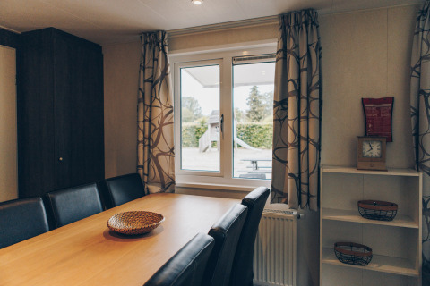 Dining room at Dune Lodge in Duinhoeve, Netherlands, modern wooden table, leather chairs, window view.
