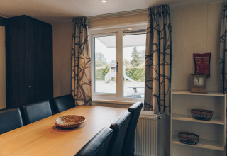 Dining room at Dune Lodge in Duinhoeve, Netherlands, modern wooden table, leather chairs, window view.