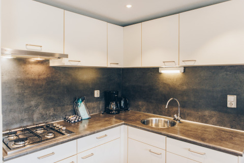 Modern kitchen at Dune Lodge in Duinhoeve, Netherlands, featuring stove, sink, and coffee maker.