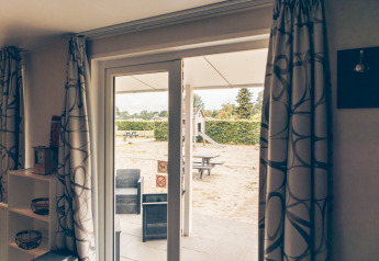 Blick aus dem Inneren der Dune Lodge in Duinhoeve, Niederlande, auf den Außenbereich mit Spielplatz.