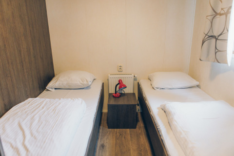 A room at Dune Lodge in Duinhoeve, Netherlands, featuring twin beds and a nightstand with a red lamp.