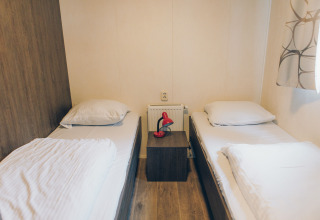 A room at Dune Lodge in Duinhoeve, Netherlands, featuring twin beds and a nightstand with a red lamp.