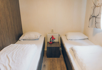 Zimmer im Dune Lodge bei Duinhoeve, Niederlande, mit zwei Einzelbetten und Nachttisch mit roter Lampe.