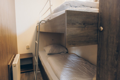 Room with wooden bunk beds and a radiator, photographed at Dune Lodge in Duinhoeve, the Netherlands.