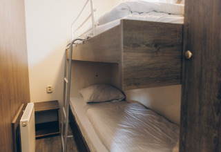 Room with wooden bunk beds and a radiator, photographed at Dune Lodge in Duinhoeve, the Netherlands.