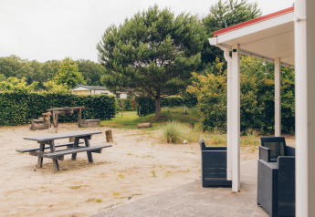 Vista di terrazza e parco giochi alla Dune Lodge a Duinhoeve, Paesi Bassi, tra verde e sabbia.
