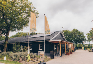 Front view of Dune Lodge at Duinhoeve, Netherlands, featuring a black building and two yellow flags.