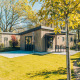 Moderne Loevestein Comfort lodge met bubbelbad, terras en grasveld, omgeven door zonnige bomen.
