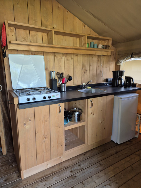 Kleine Küchenzeile in einem Safarizelt auf Camping De Rammelbeek in den Niederlanden mit Herd und Kühlschrank.