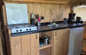 Kleine Küchenzeile in einem Safarizelt auf Camping De Rammelbeek in den Niederlanden mit Herd und Kühlschrank.