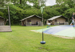 Safarizelte und Spielplatz auf dem Camping Dal van de Mosbeek in den Niederlanden mit grüner Umgebung.