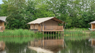 Safari-Zelt auf dem Campingplatz De Rammelbeek in den Niederlanden, auf Stelzen am ruhigen See im Grünen.