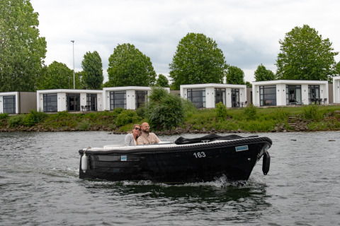 Twee mensen varen in een zwarte boot voor Villa Maritiem lodges bij MarinaPark Bad Nederrijn, Nederland.