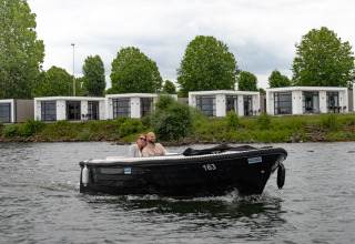 Twee mensen varen in een zwarte boot voor Villa Maritiem lodges bij MarinaPark Bad Nederrijn, Nederland.