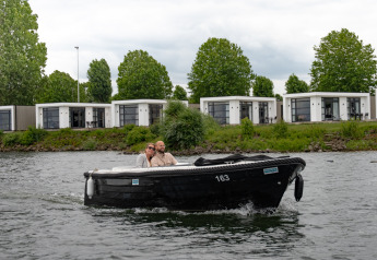 Due persone su una barca nera davanti alle ville Maritiem nel MarinaPark Bad Nederrijn, Paesi Bassi.