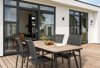 Terrasse mit Esstisch und vier Stühlen bei Villa Maritiem, MarinaPark Bad Nederrijn, Niederlande.