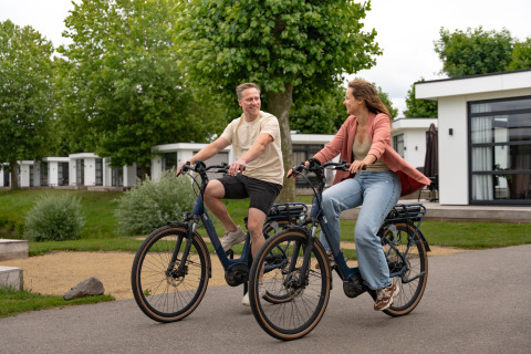 Zwei Personen fahren Fahrrad an der Villa «Maritiem» im MarinaPark Bad Nederrijn in den Niederlanden.