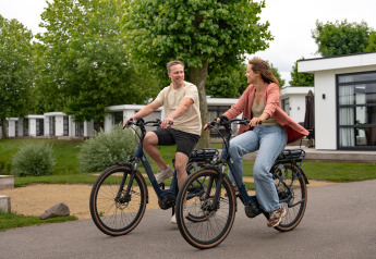 Twee mensen fietsen samen bij Villa «Maritiem» in MarinaPark Bad Nederrijn in Nederland.