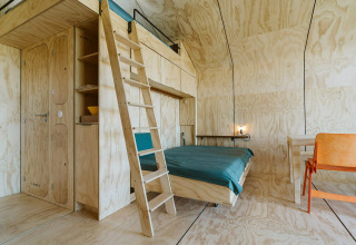 Interiør af tiny house Wikkelhouse Bear ved De Klepperstee, Holland, med trævægge og enkel indretning.