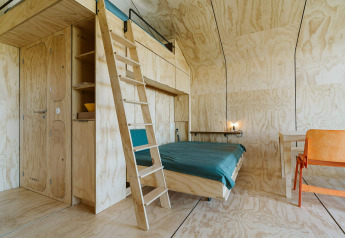 Interiør af tiny house Wikkelhouse Bear ved De Klepperstee, Holland, med trævægge og enkel indretning.