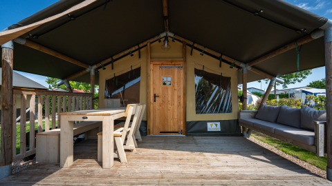 Safaritent ‘Compact’ op Camping de Molenhoek in Nederland met houten terras, tafel en comfortabele zitbank.