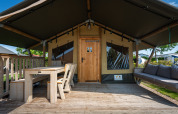 Tenda safari “Compact” al Camping de Molenhoek nei Paesi Bassi con veranda in legno, tavolo e comode panche.