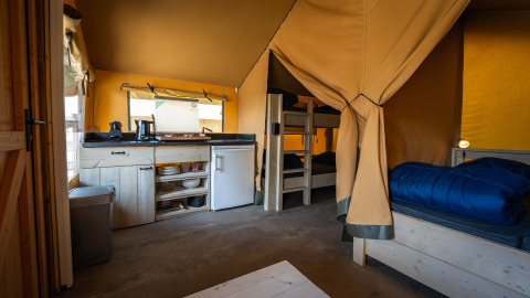 Compact safaritent op Camping de Molenhoek in Nederland met keuken, stapelbedden en eettafel.