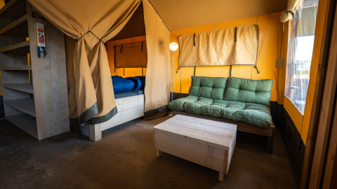 Interieur van een Compact safaritent op Camping de Molenhoek in Nederland, met zitbank en bed.