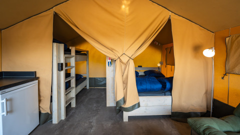 Binnenzicht van de safaritent 'Compact' met stapelbedden en dubbel bed op Camping de Molenhoek, Nederland.