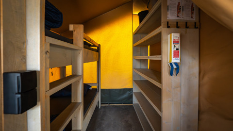 Binnenzicht van een Compact safaritent op Camping de Molenhoek met stapelbedden en houten rekken.
