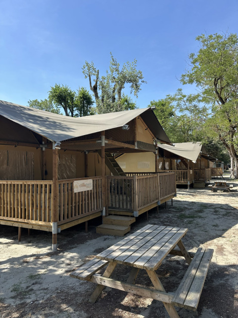 Safaritent ‘Ranger’ op Camping Spina Family Collection in Italië met houten terras en picknicktafel buiten.