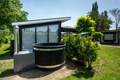 Black outdoor hot tub in front of a modern Bos Lodge at Vacation center 't Schuttenbelt in the Netherlands.