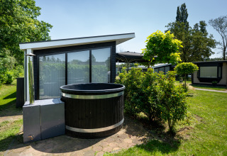 Black outdoor hot tub in front of a modern Bos Lodge at Vacation center 't Schuttenbelt in the Netherlands.