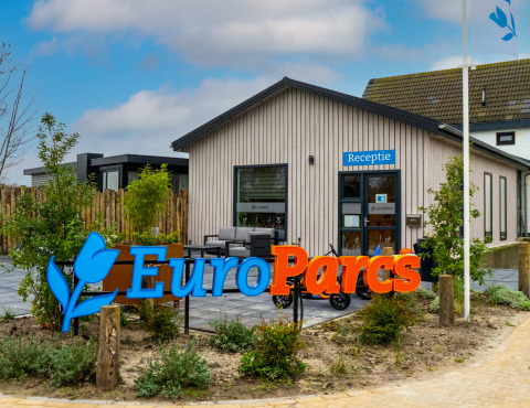 EuroParcs lodge reception building with blue Receptie sign, modern exterior, and landscaping in front.